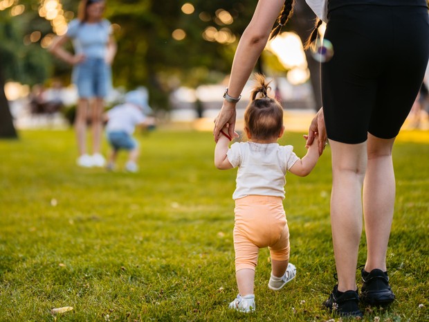 woman walking a small child through the park