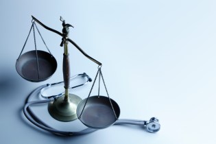 Stethoscope wrapped around a metal scale of justice
