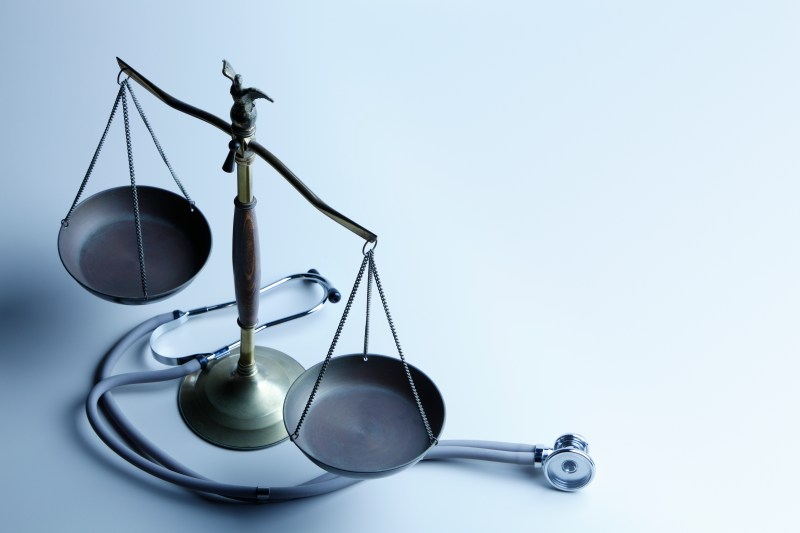 Stethoscope wrapped around a metal scale of justice
