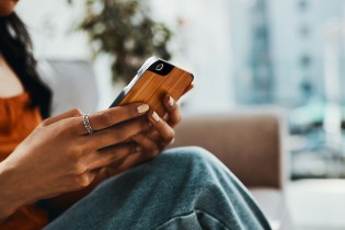 Woman in an orange blouse using an app on her smartphone.