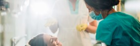 Smiling woman sitting in dentist chair and talking to her dentist before teeth examination.