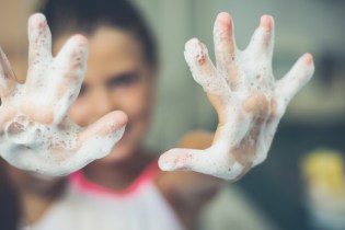 Blurry image of woman with soapy hands in foreground.