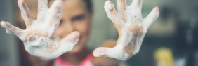 Blurry image of woman with soapy hands in foreground.