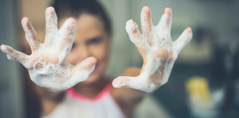 Blurry image of woman with soapy hands in foreground.