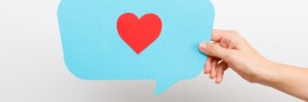 Hand holding a blue speech bubble with a red heart inside