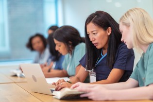 Asian-American nurse educator helping student on computer
