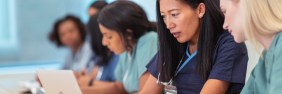 Asian-American nurse educator helping student on computer
