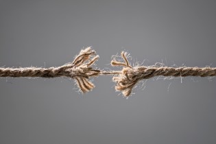 Two pieces of frayed rope connected by a single thread