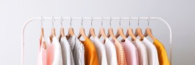 A clothing rack holding a variety of women's blouses in different shades of white, yellow, and pink.