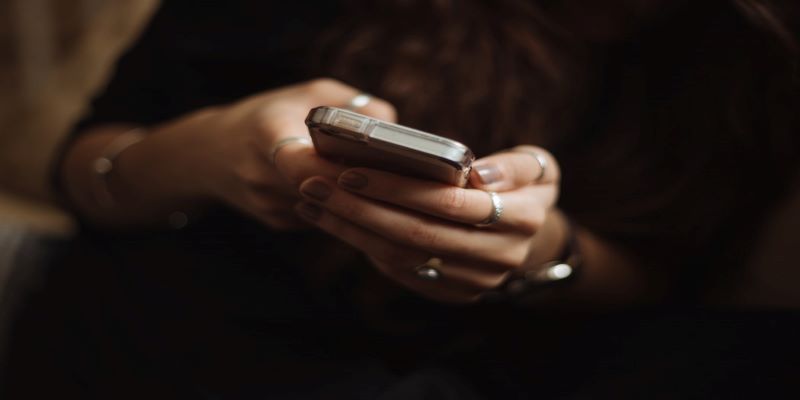 Pair of female hands with rings texting on a smartphone