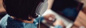 Woman with Beats headphones listening to podcasts while on laptop.