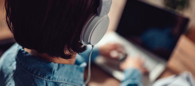 Woman with Beats headphones listening to podcasts while on laptop.