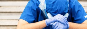 healthcare worker in blue scrubs with head down