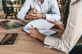 Man consulting with female attorney who is writing notes on a clipboard.