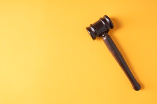 Plain brown gavel against yellow background