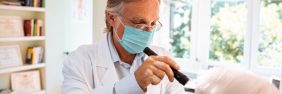 optometrist in mask giving patient an eye exam