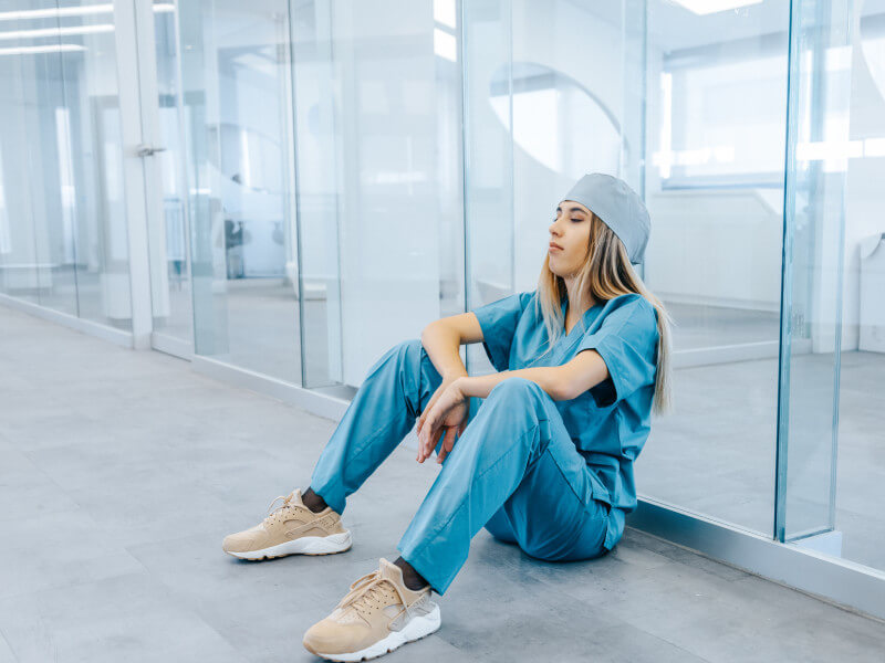 nurse sitting in blue scrubs during a nursing shortage
