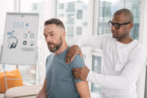 Male physical therapist working with a male client in a physical therapy office