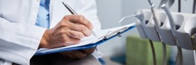 dentist writing a dental incident report on a clipboard