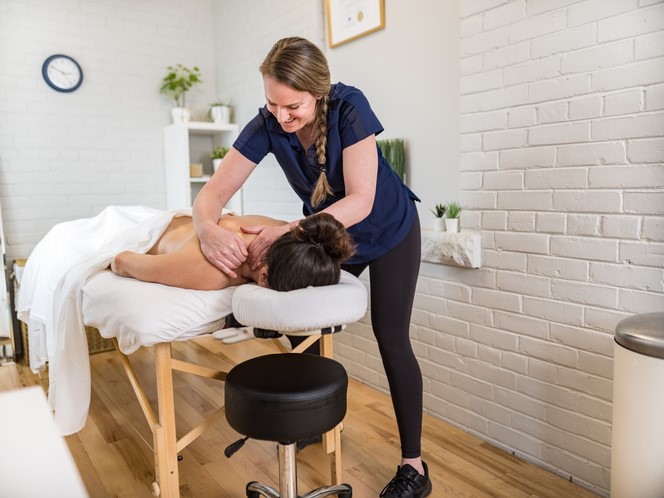 Woman giving client a massage on a massage table | Factors That Impact General Liability Insurance Costs