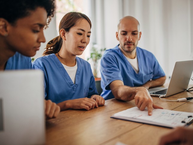 Nurses gathered around conference table reviewing their employer's malpractice insurance coverage 