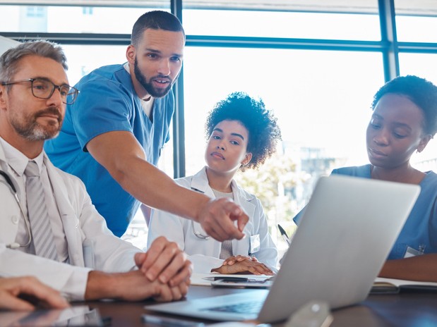 Healthcare professionals gathered around a laptop discussing different types of insurance