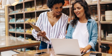 Two women searching on laptop at work