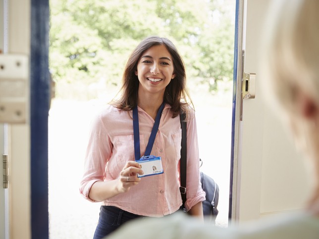 Smiling woman showing her social worker name badge | Social worker malpractice insurance coverage requirements