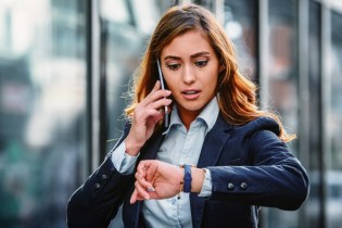 Woman checking her watch while on a phone call asking when to buy professional liability insurance
