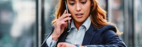Woman checking her watch while on a phone call asking when to buy professional liability insurance
