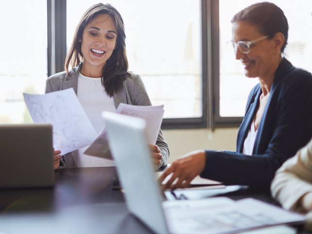 Two women discuss berxi insurance at a conference table 