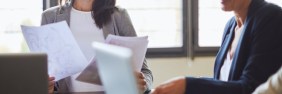 Two women discuss berxi insurance at a conference table