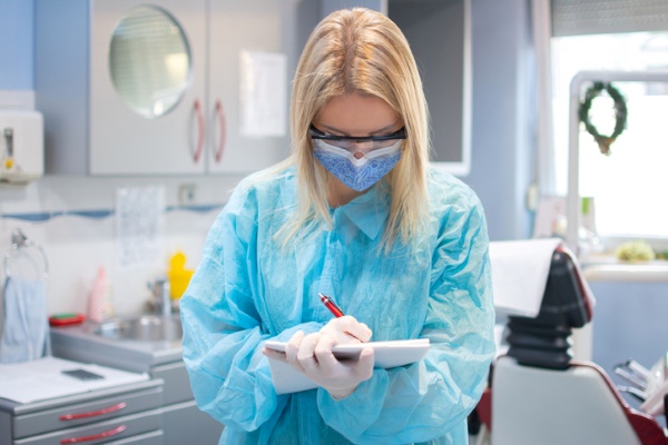 dentist in scrubs taking notes about dental malpractice insurance