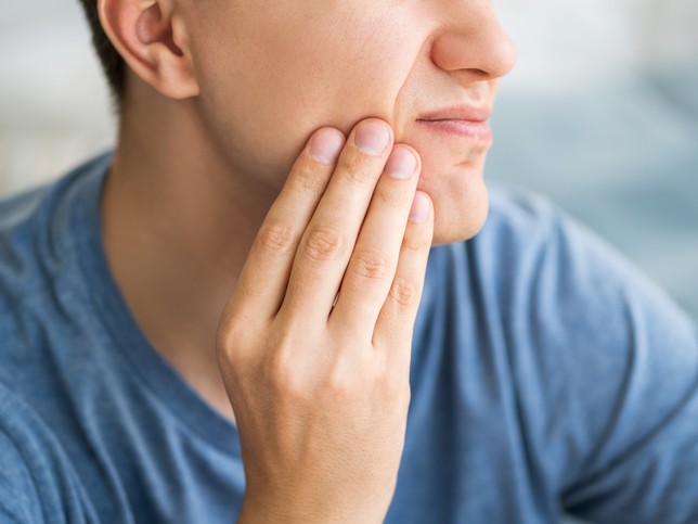 Man holding his tooth in pain | dental malpractice stories