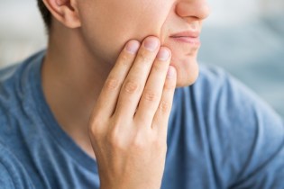 Man holding his tooth in pain | dental malpractice stories