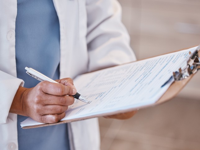 dentist writing risk mitigation reports on a clipboard 
