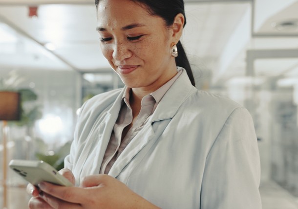 Female dentist on her phone searching for dental malpractice insurance cost | Dental Malpractice Insurance Cost Guide