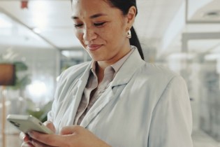 Female dentist on her phone searching for dental malpractice insurance cost | Dental Malpractice Insurance Cost Guide