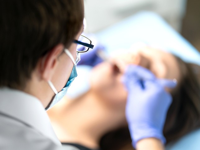 female dentist treating patient while wearing gloves