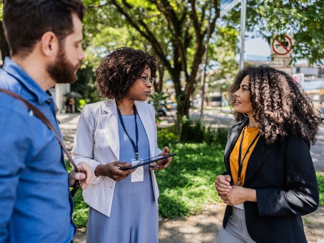 Female dentist speaking with man and woman on the sidewalk 