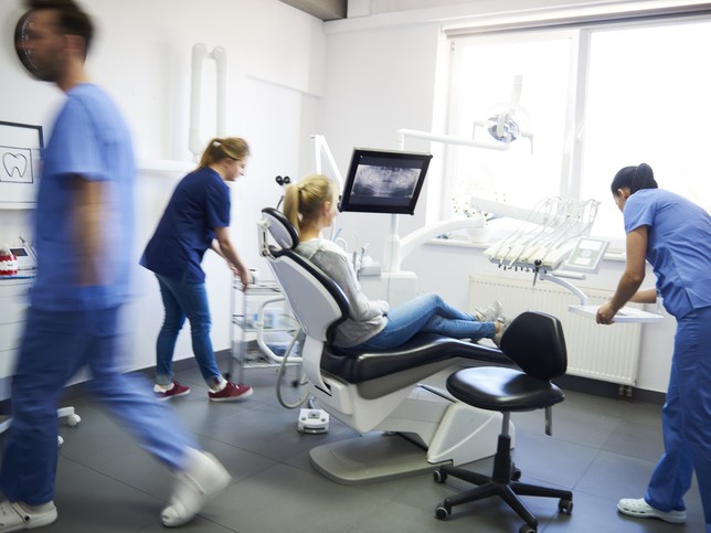 Dental team working with female patient in dental chair 