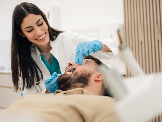 female dentist treating male patient in dental chair