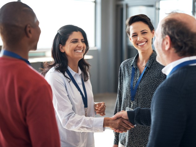 group of dental professionals shaking hands and talking at a dental conference