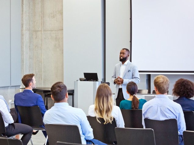 periodontist giving a lecture to a crowd at a dental conference