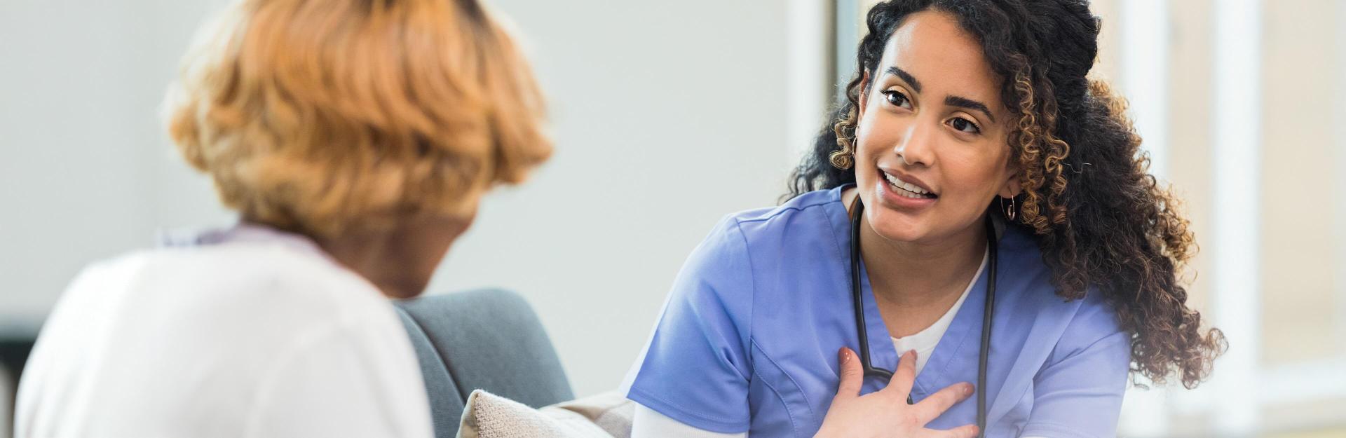 female nurse sitting with patient | compare nursing malpractice insurance