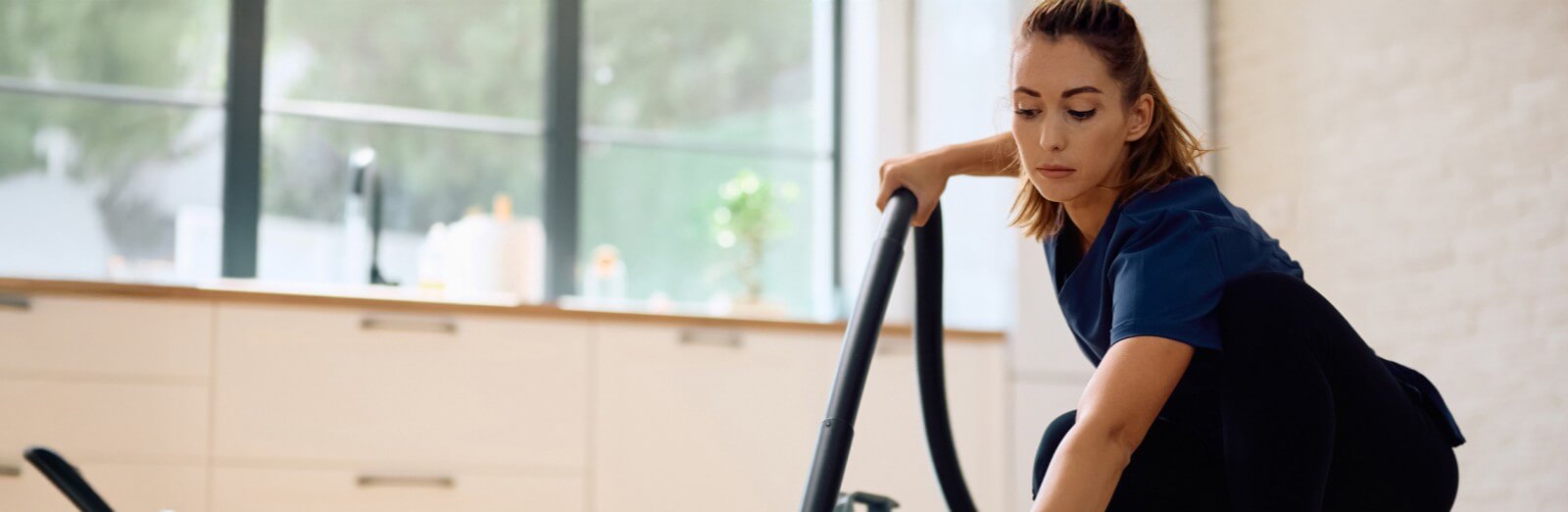 woman vacuuming a kitchen | house cleaning liability insurance