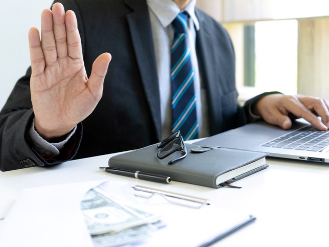 man in suit holding up hand and working on laptop | nurse practitioner malpractice claim