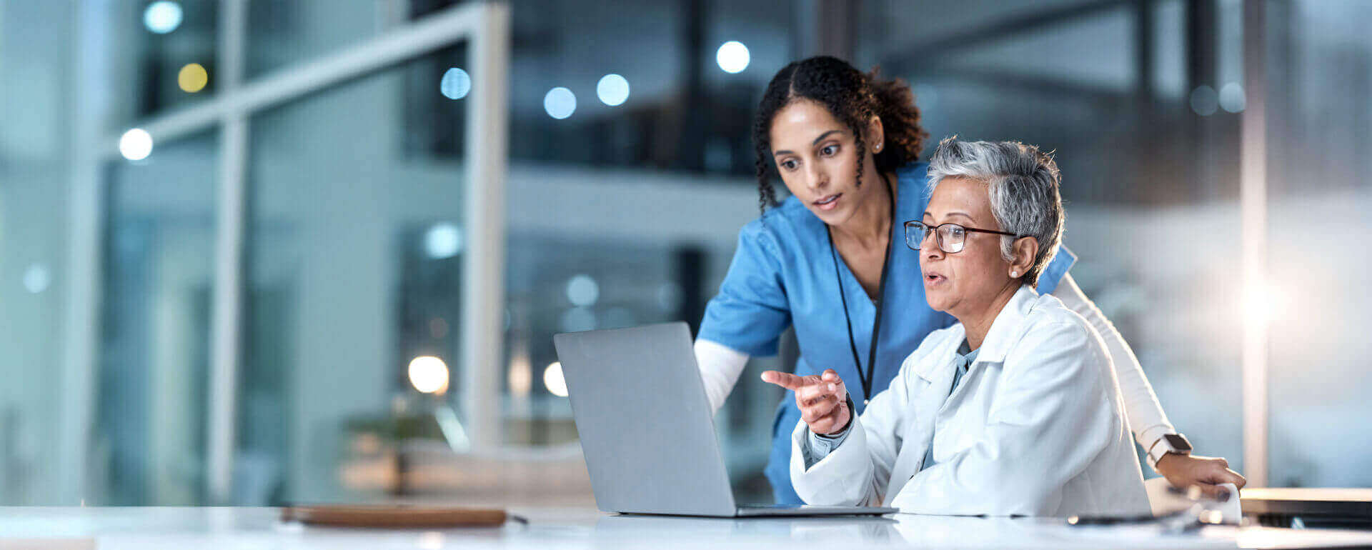 Nurse practitioner and colleague working on laptop | malpractice insurance for np