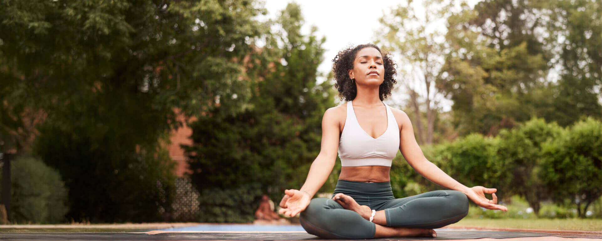 Yoga instructor in meditative position outside | yoga teacher liability insurance