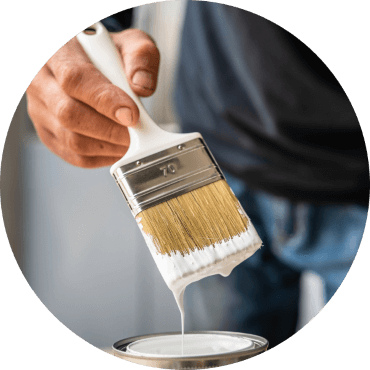 Painter with dripping paintbrush over open paint can